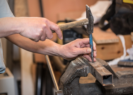 Male hands of builder man holding hammer and scored. Closeup photo