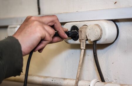 Man hand holding and pull electronic plug. Unplug or plugged in concept.