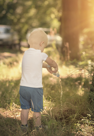 Little boy watering the grass in park a sunny dayの写真素材