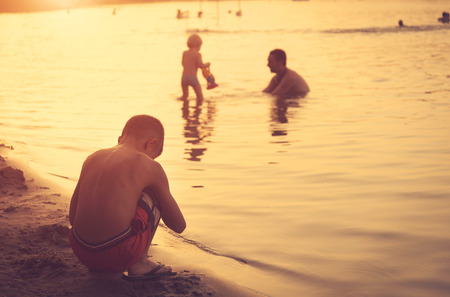 Young boy play on the beach in sunsetの写真素材