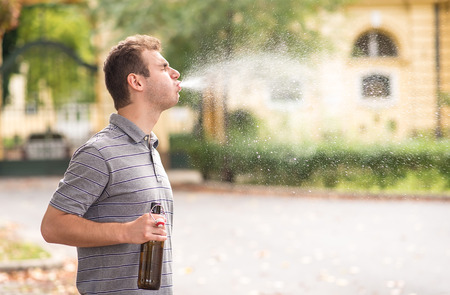 Young man spit out alcohol in the parkの写真素材