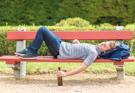 Young man relaxing in a bench in the park after partyの写真素材