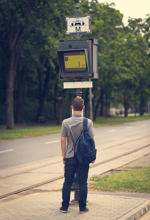 Student guy waiting for a tram at the tram stopの写真素材