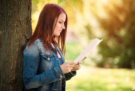 Beauty woman reading a document in the parkの写真素材
