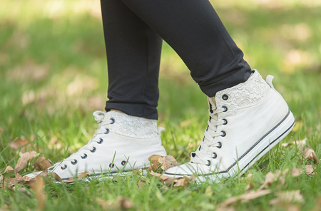 Woman in white sneakers on the grass an autumn dayの写真素材