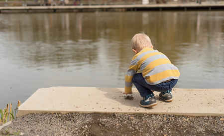 Little boy playing near the lake in the parkの写真素材