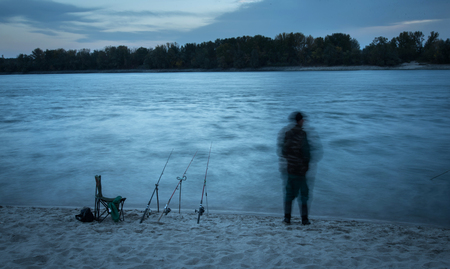 Motion blurred fisherman on the beach. Blue toned photoの写真素材