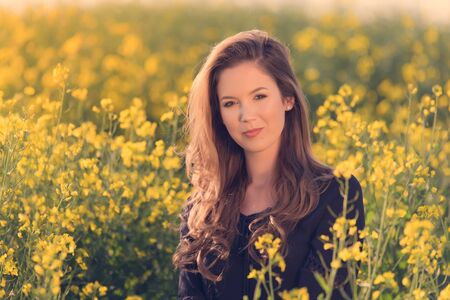 Portrait of beautiful woman in rapeseed field at sunset