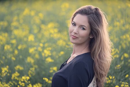 Beautiful woman in rapeseed field. Soft toned photoの写真素材