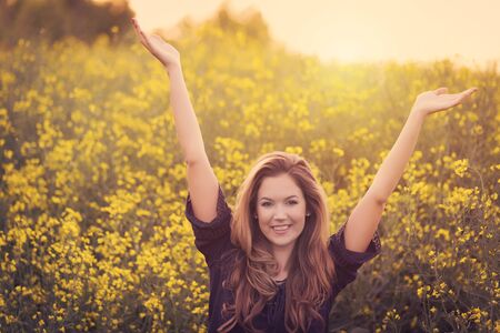 Beauty smiling woman in yellow rapeseed field at sunset
