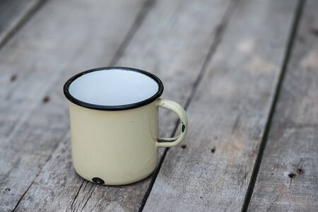 Old metal cup on a wooden tableの写真素材