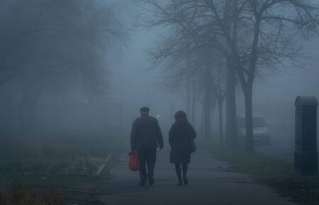 Old couple walking on the street a foggy dayの写真素材