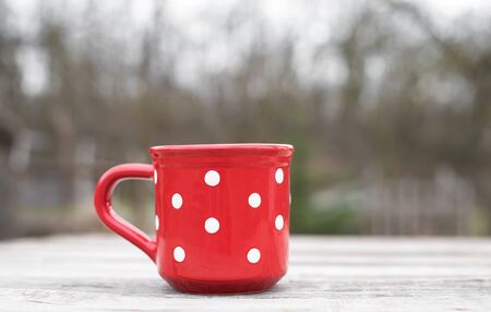 Red polka dot mug on a wooden tableの写真素材