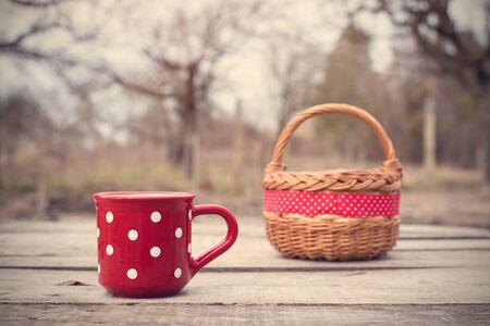 Red polka dot mug with basket on a wooden tableの写真素材
