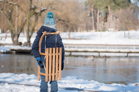 Child with a wooden sled in the park on a winters dayの写真素材
