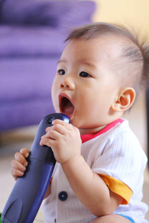 Oriental baby with TV remoteの写真素材