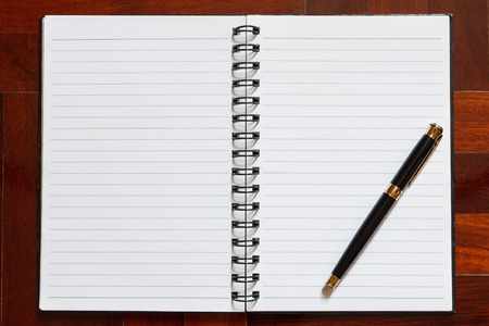 Notebook and pen. Blank white page. Wooden floor in the background.の写真素材