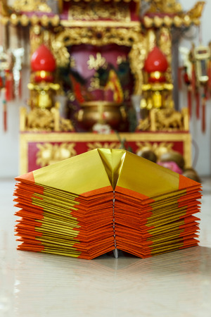 Chinese paper art use for worship.And a shrine in the background.Focus on the top paper.の写真素材