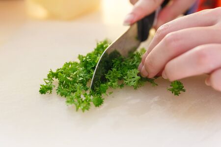 Chef chopping Parsley with knife on plastic board.の写真素材