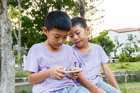 Thai twin boy playing mobile phone.の写真素材