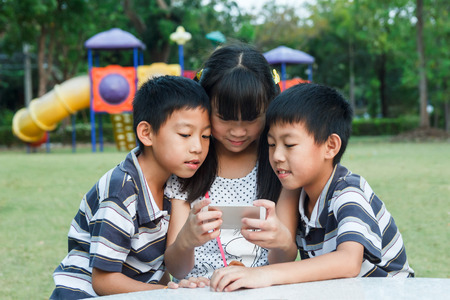 Sister and twin brother using smartphone with fun.の写真素材