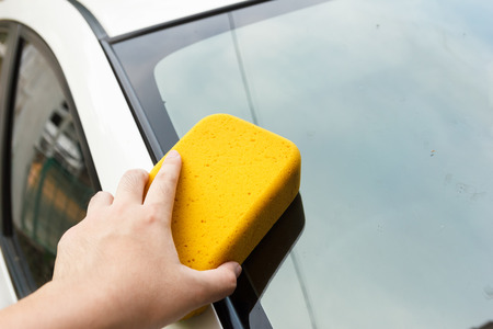 Hand cleaning car's dirt with yellow sponge.の写真素材