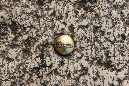 Verona, Italy - December 9, 2016: Detail of street bolt on road with the City of Verona crest.のeditorial素材