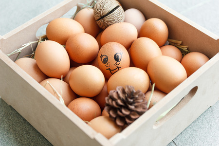 Smiling face on egg with hay and pine in the box.の写真素材