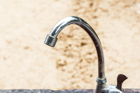 Grunge faucet with dry ground in background.の写真素材