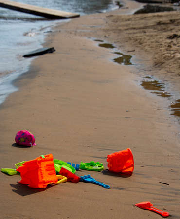 Children's toys on the warm sand of the beach of a wild lake in Quebec, Canada