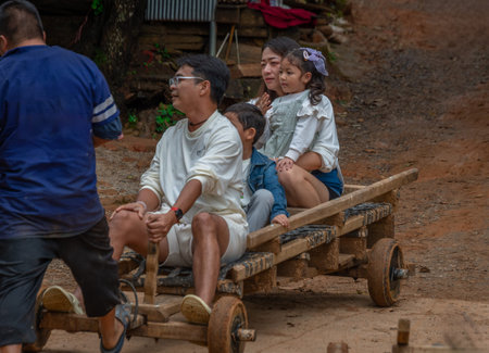 A family of tourists taking a ride in a small sleigh through the mountain countryside of Thailand.のeditorial素材