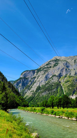 Power lines over the Saalach River in the Alpine Mountainsの写真素材