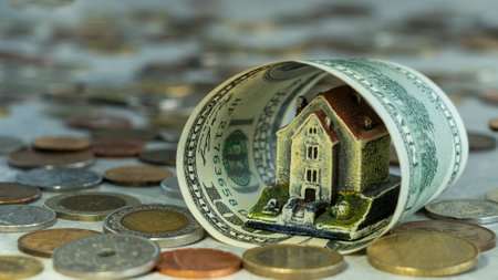 The house is wrapped in a hundred dollar bill with different coins, the concept of the real estate market, financial protection, rising housing costs, utility bills, fluctuating moの写真素材