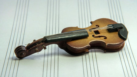 A miniature violin lies on top of the sheet musicの写真素材