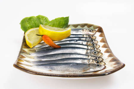 Fresh fish on plate with lemon peppers on white backroundの写真素材