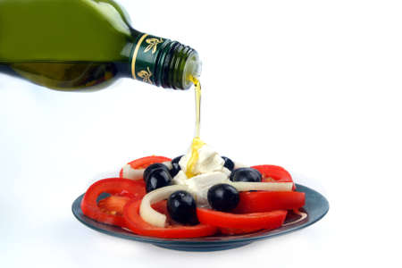 Olive oil being poured over a salad against white backroundの写真素材
