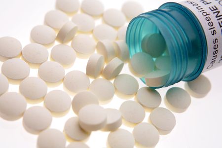 Pills spilling from plastic container on white