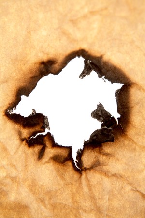 Hole burnt in brown paperの写真素材
