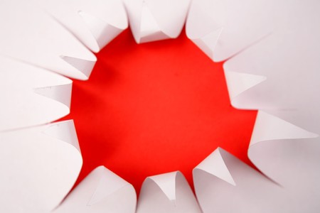 Hole in white paper over redの写真素材