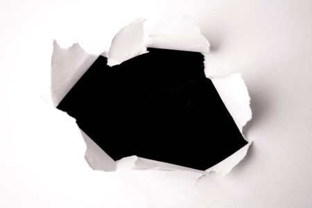Hole in white paper over blackの写真素材