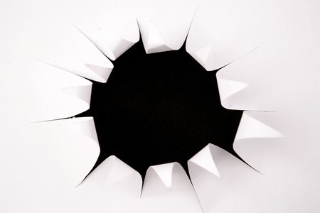 Hole in white paper over blackの写真素材