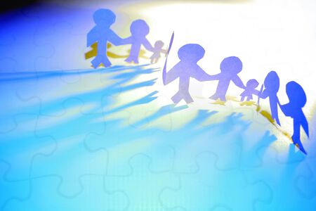 Paper doll team holding hands and jigsaw puzzle.の写真素材