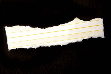 Ripped lined paper over dark surfaceの写真素材