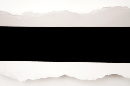 Hole ripped in white paper on blackの写真素材