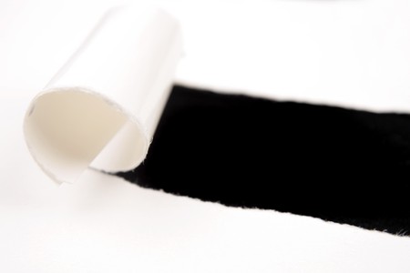 Hole ripped in white paper on blackの写真素材