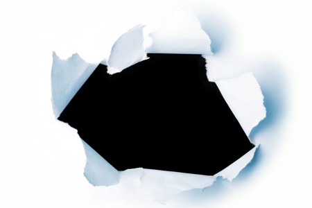 Hole ripped in paper on blackの写真素材