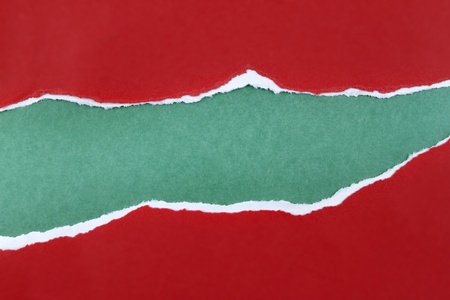 Hole ripped in red paper on green background. Copy spaceの写真素材