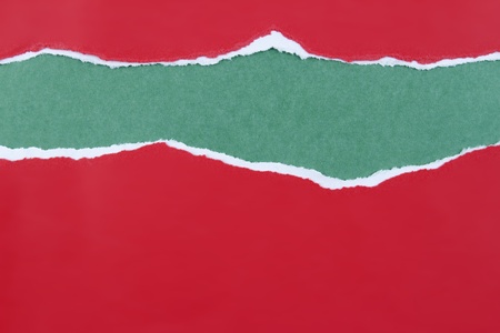 Hole ripped in red paper on green background. Copy spaceの写真素材