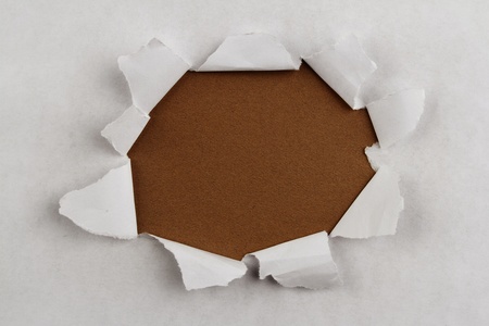 Hole ripped in paper on brown backgroundの写真素材
