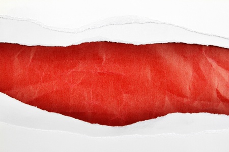 Hole ripped in white paper on red backgroundの写真素材